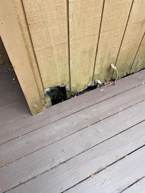 Outside main floor bedroom deck, large hole in the house needing repair.