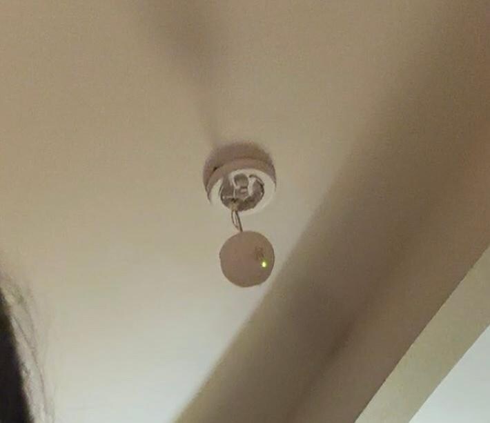 Smoke detector hanging from ceiling. It did appear functional as the light was on. 