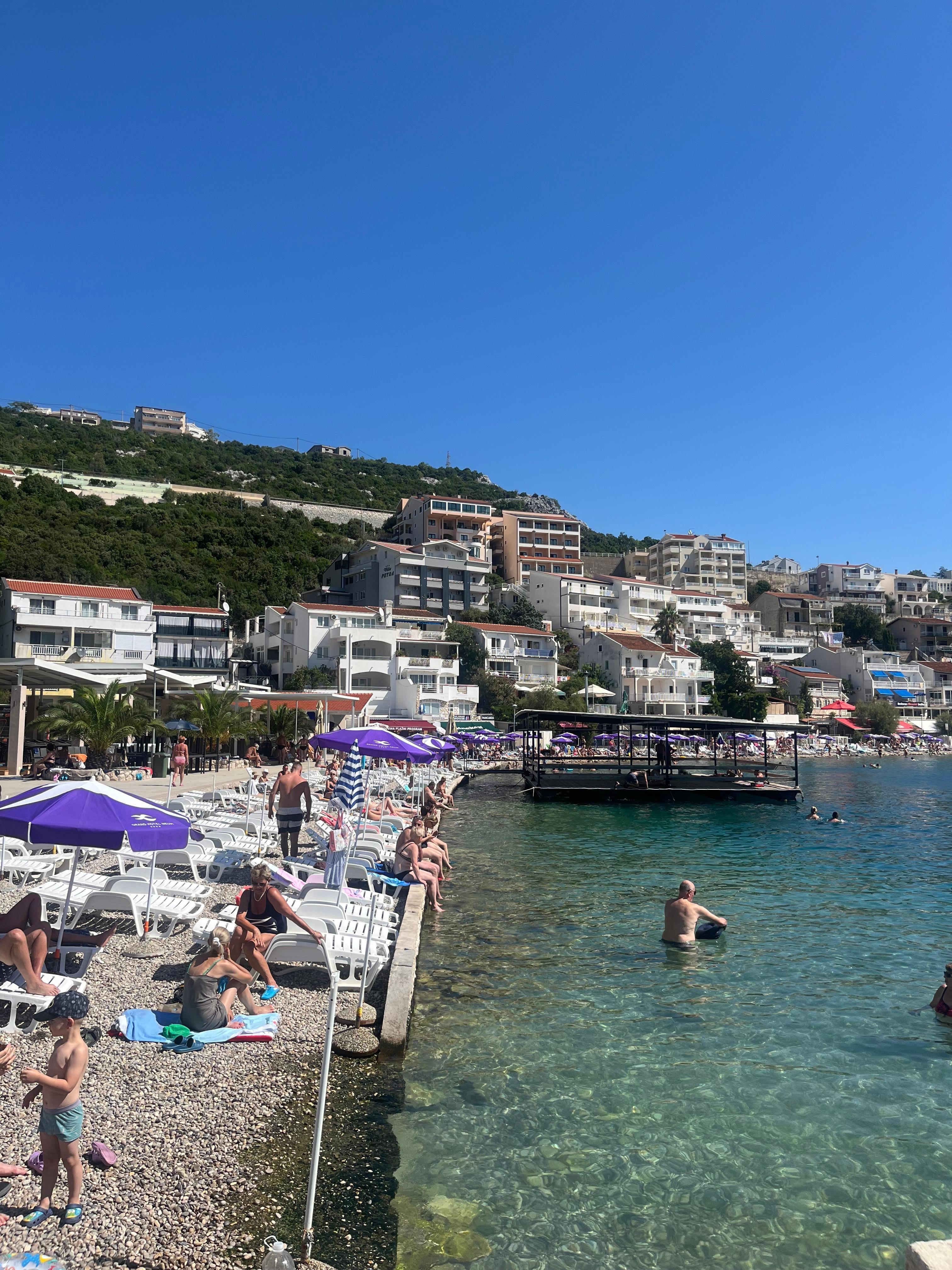 Badstrand med vackert klart vatten nedanför hotellet.