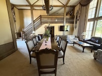 The great room with dining table and chairs for 10 with a sitting area for 4 next to it. A loft at the top of the stairs also has a sitting area.