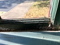 rotting window frame with hole to outside and cobwebs all over sill and window frames