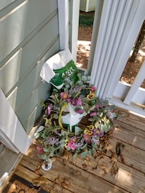 Next to front door- de-icer (in July) and wreath on ground