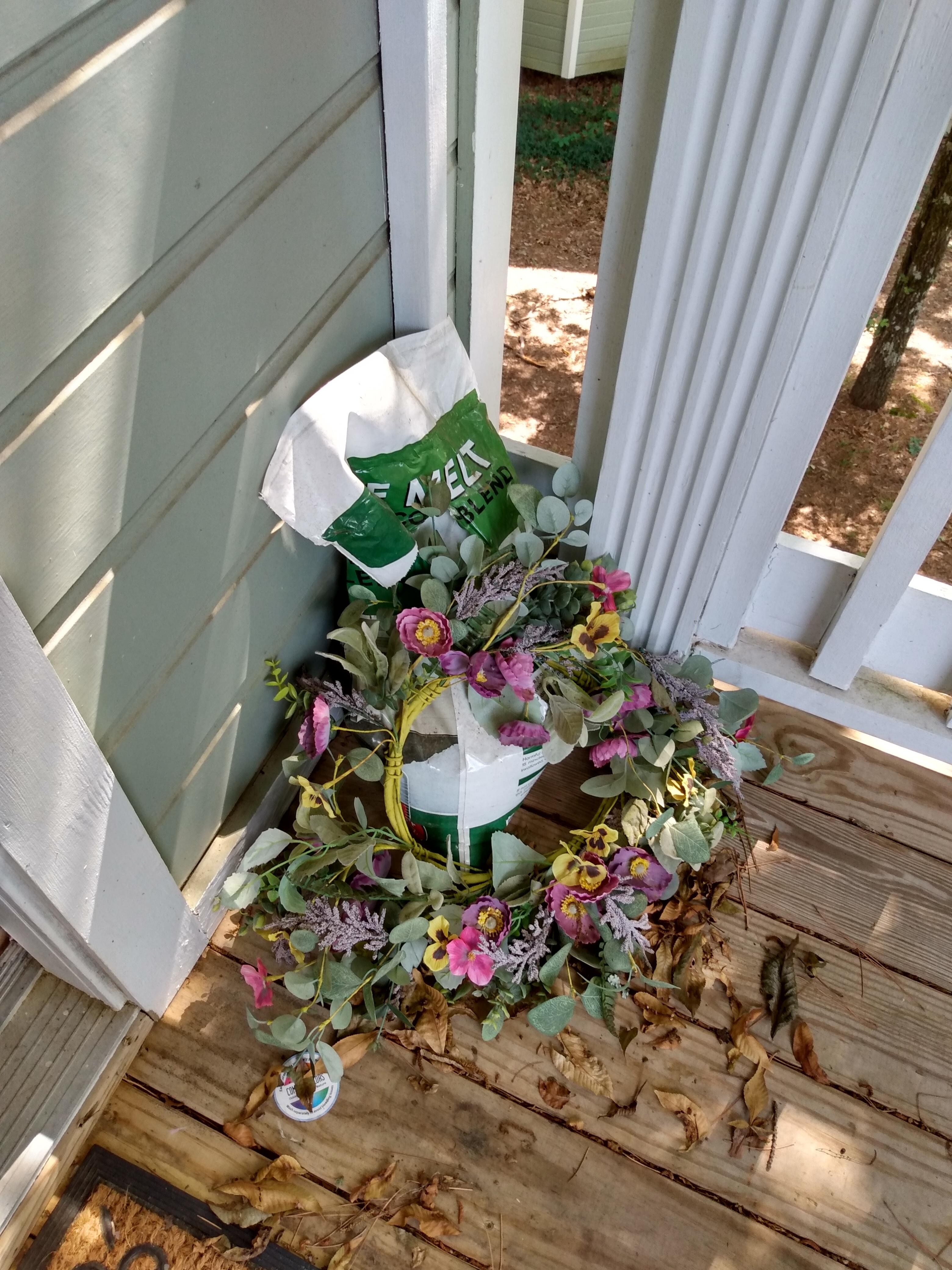 Next to front door- de-icer (in July) and wreath on ground