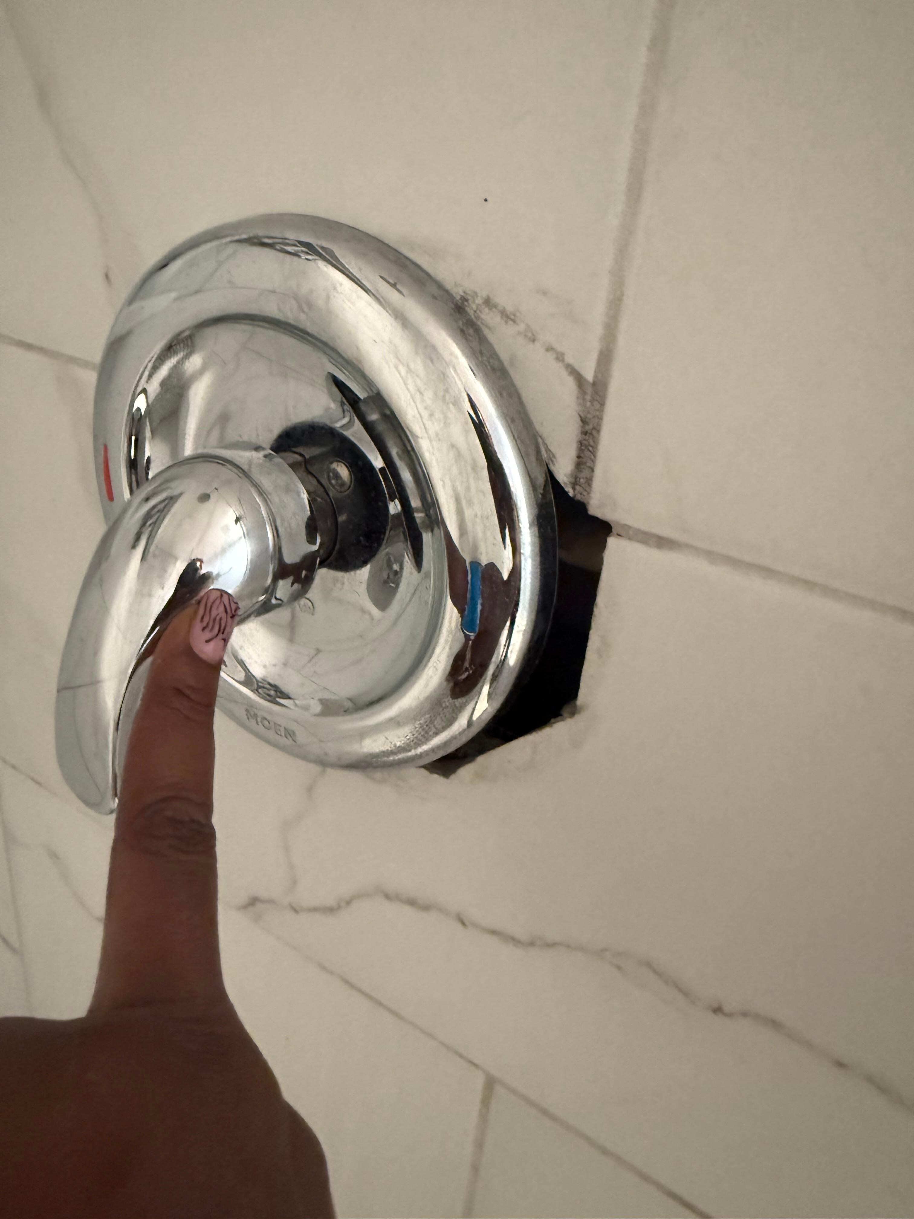 Loose shower knob showing hole in wall