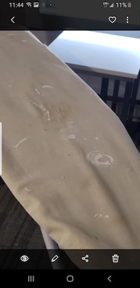 Ironing board with drywall and glue on it with a half broken iron.