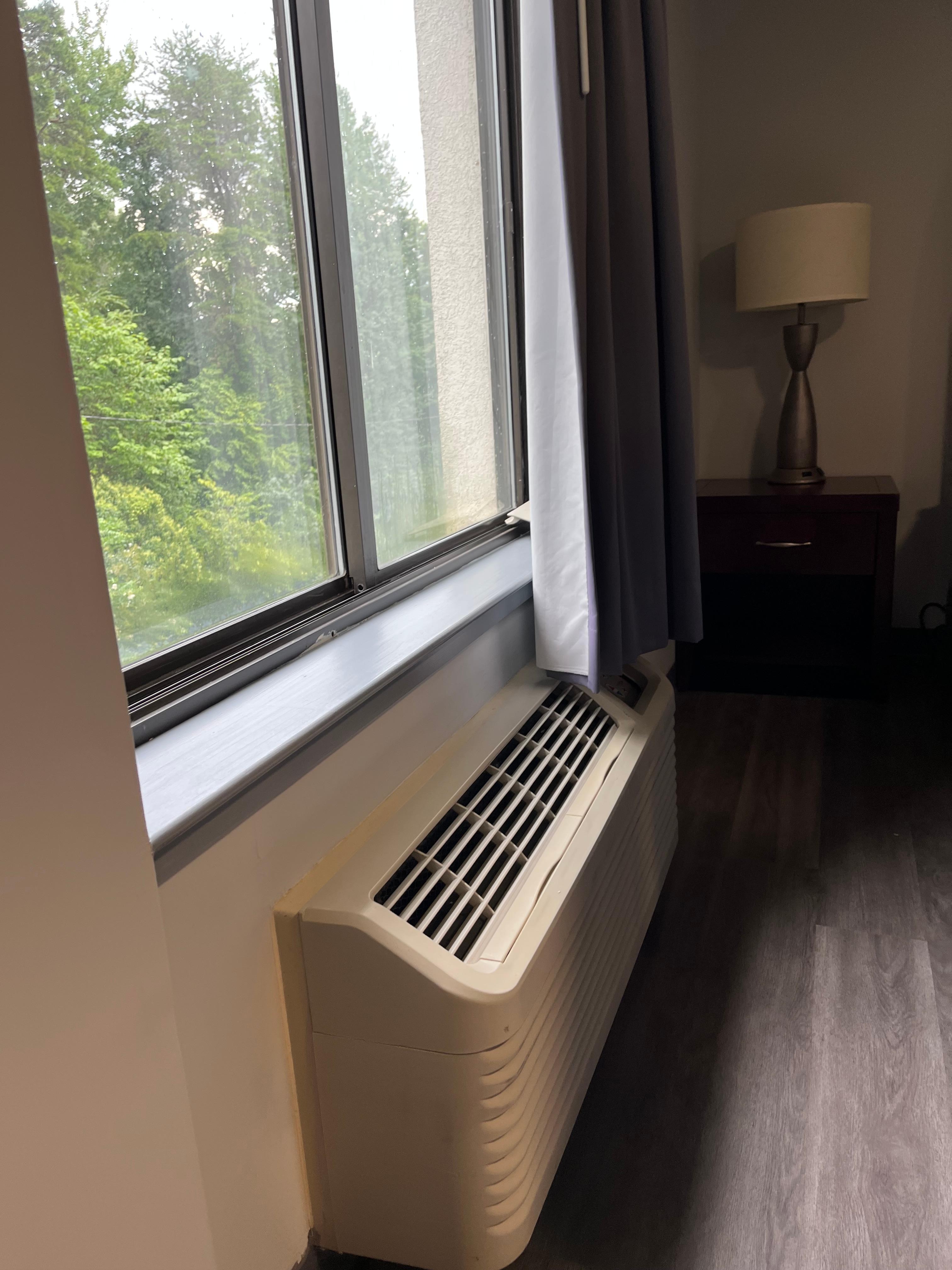 Broken lid to air conditioner behind the curtain on window ledge