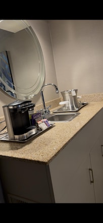 The bar area including a refrigerator, microwave and sick with coffee maker.