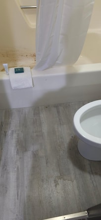 Towel laid over the tub with soaps, right in front of the gross tub