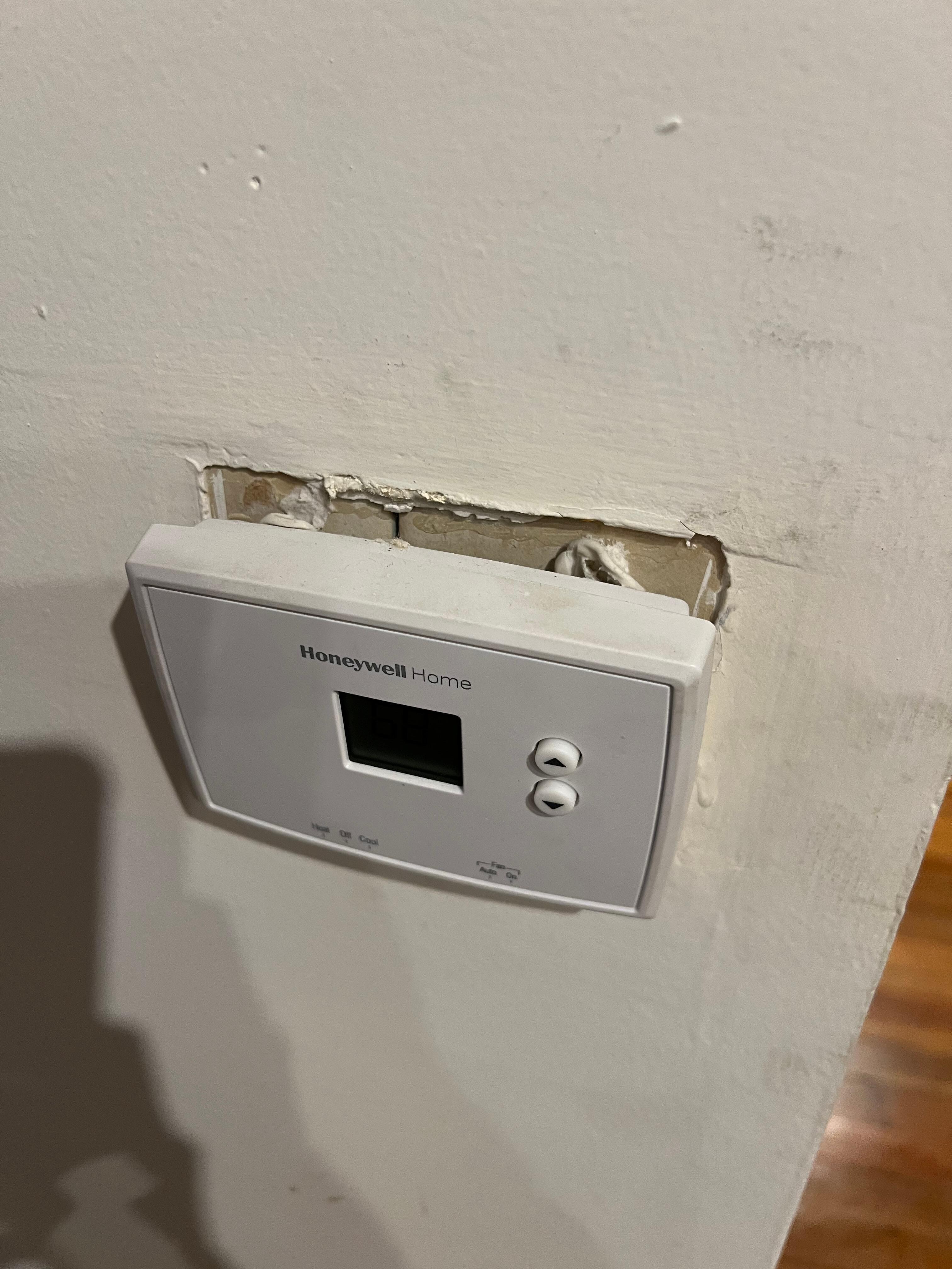 Thermostat hanging off the wall