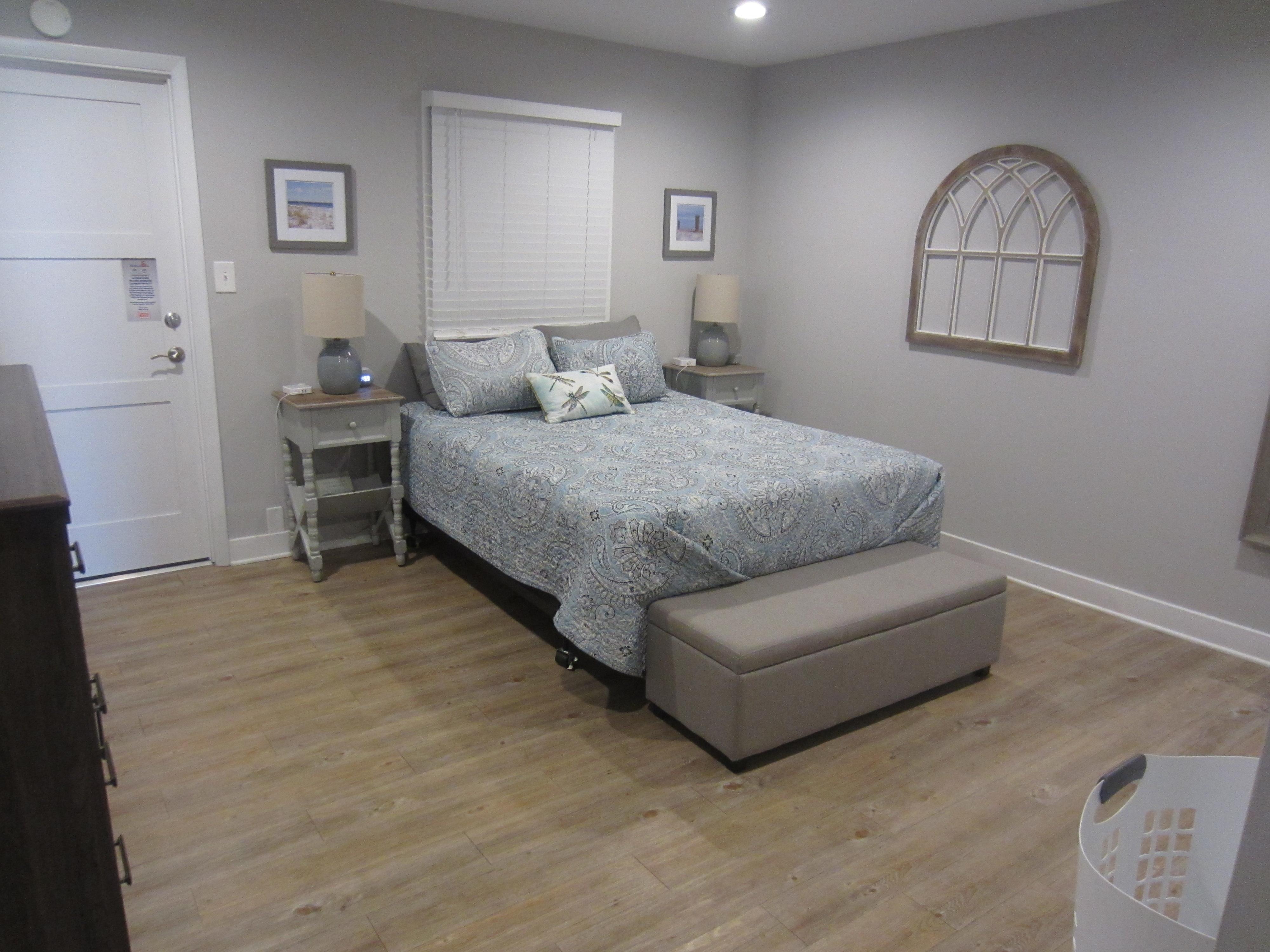 Spacious main bedroom with a dresser and closet with hangers, night tables with charging stations and sound machine.