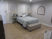 Spacious main bedroom with a dresser and closet with hangers, night tables with charging stations and sound machine.