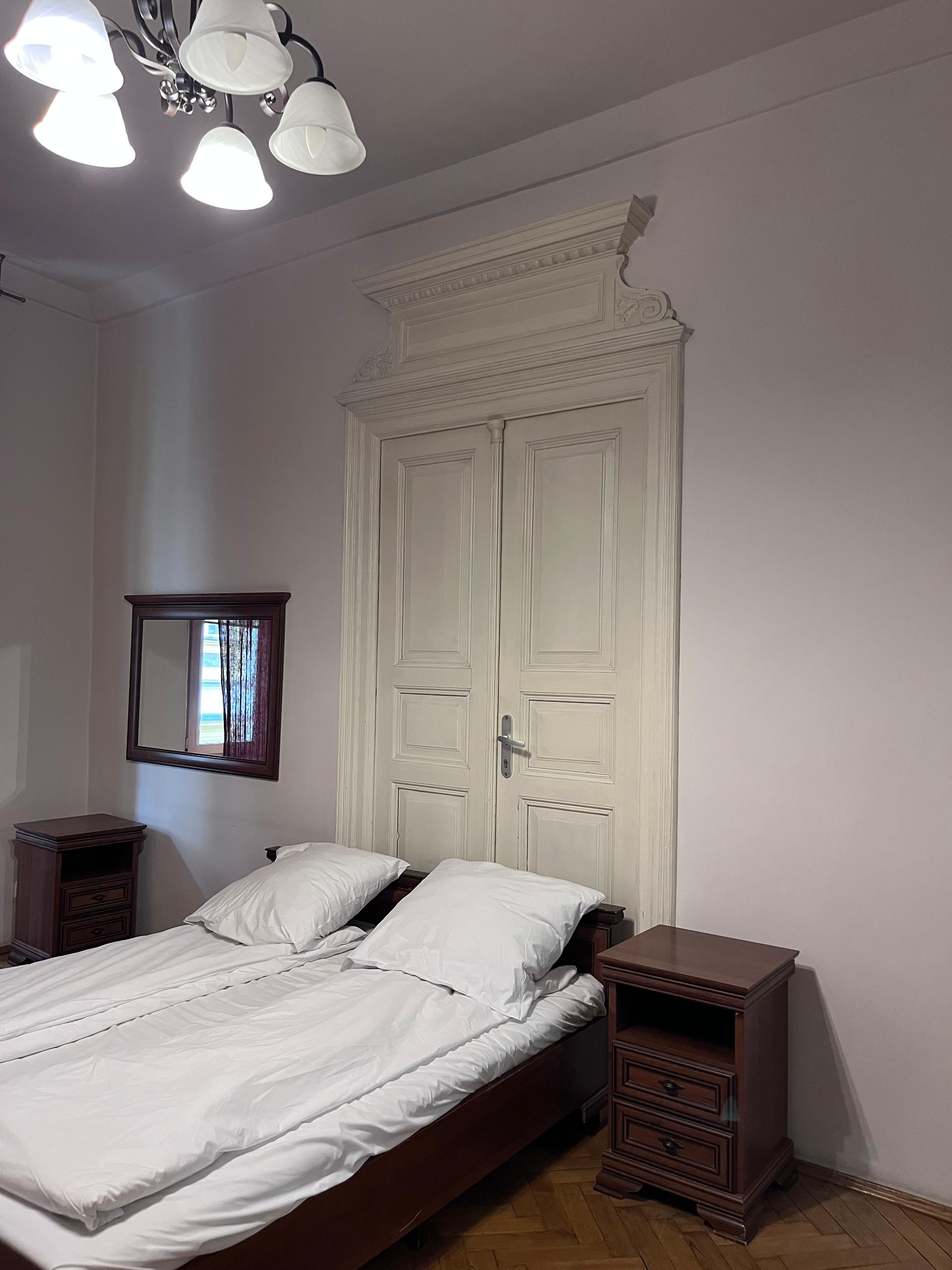 Letto posizionato davanti a una porta, senza luci di cortesia né prese elettriche accanto ai comodini.