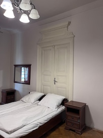 Letto posizionato davanti a una porta, senza luci di cortesia né prese elettriche accanto ai comodini.