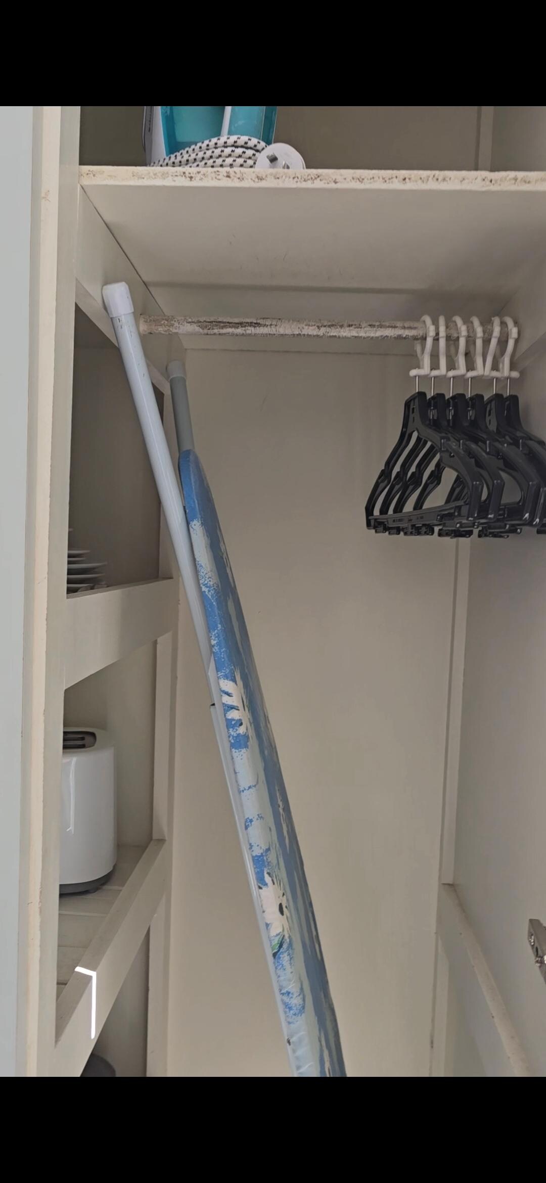 You need to remove the ironing board to use the wardrobe.
However there's no aesthetically pleasing place to situate the ironing board or even an appropriate place to stow the ironing board.