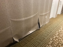 Water damage with drywall removed under and wall paper hanging to cover gaps