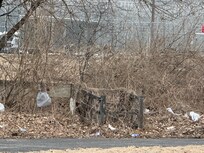 Trash behind motel. Lots of cigarette butts and empty liquor bottles and cans strewn along the back door of motel.