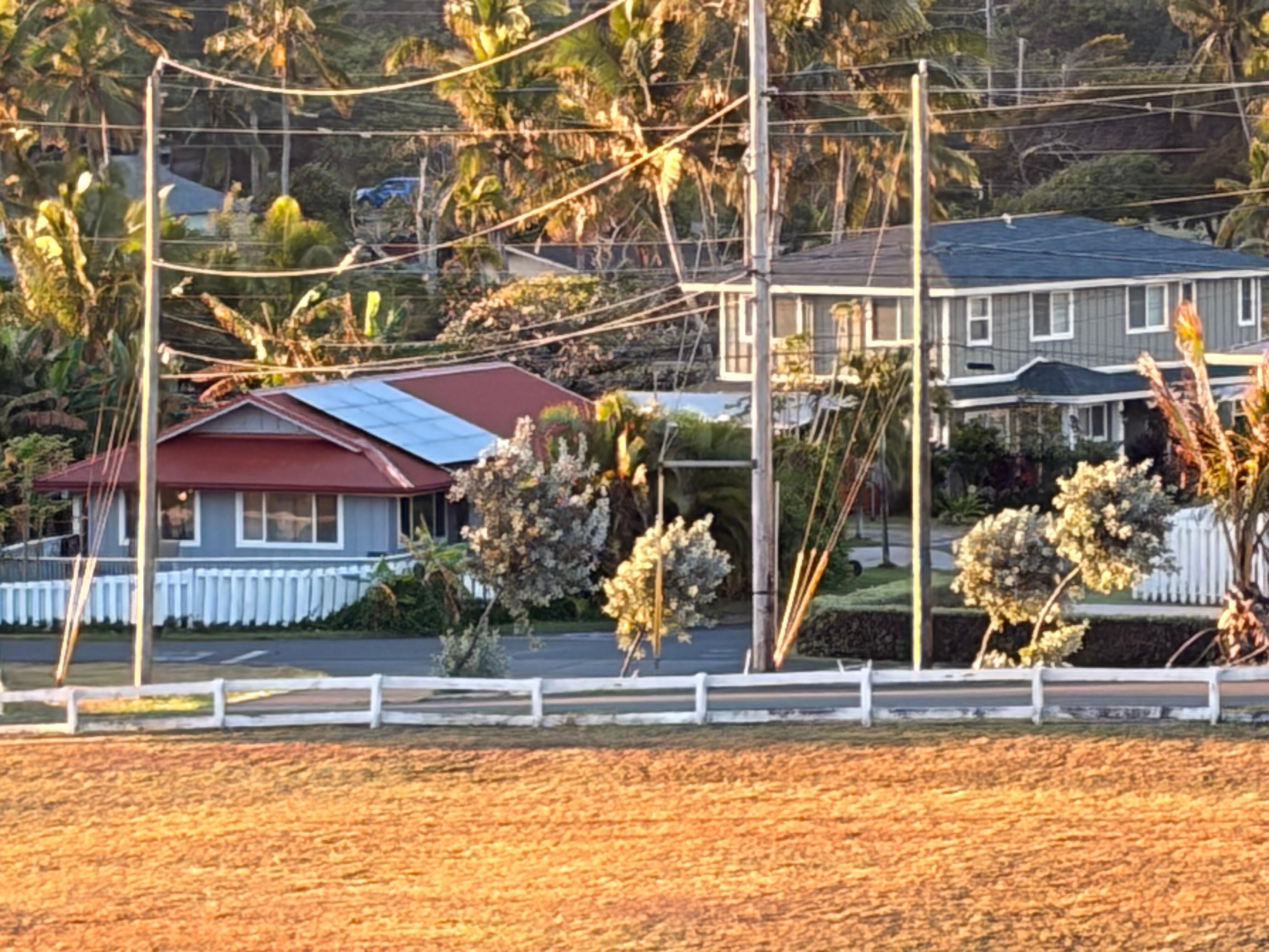 Grey house, red roof, white fence.