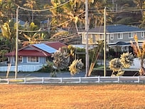 Grey house, red roof, white fence.