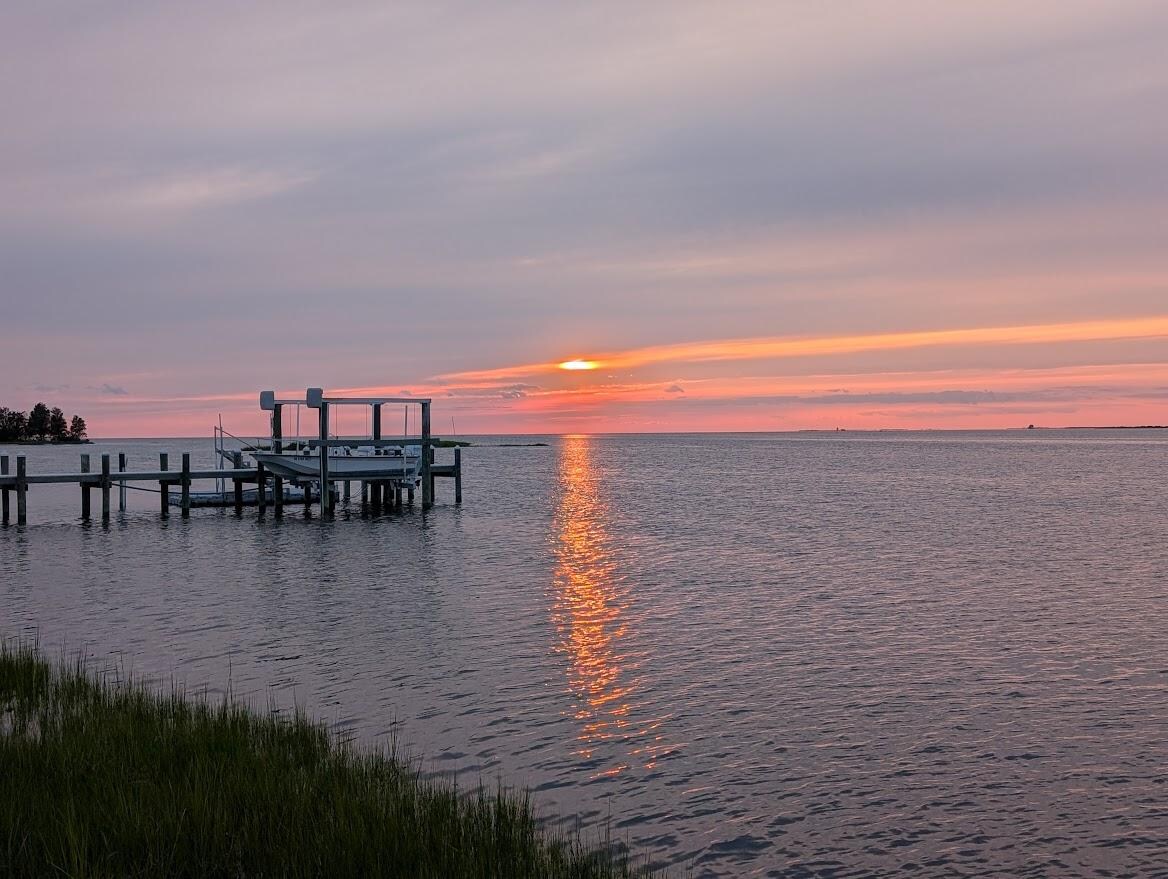 The view from the adirondack chairs toward the bay at sunset,