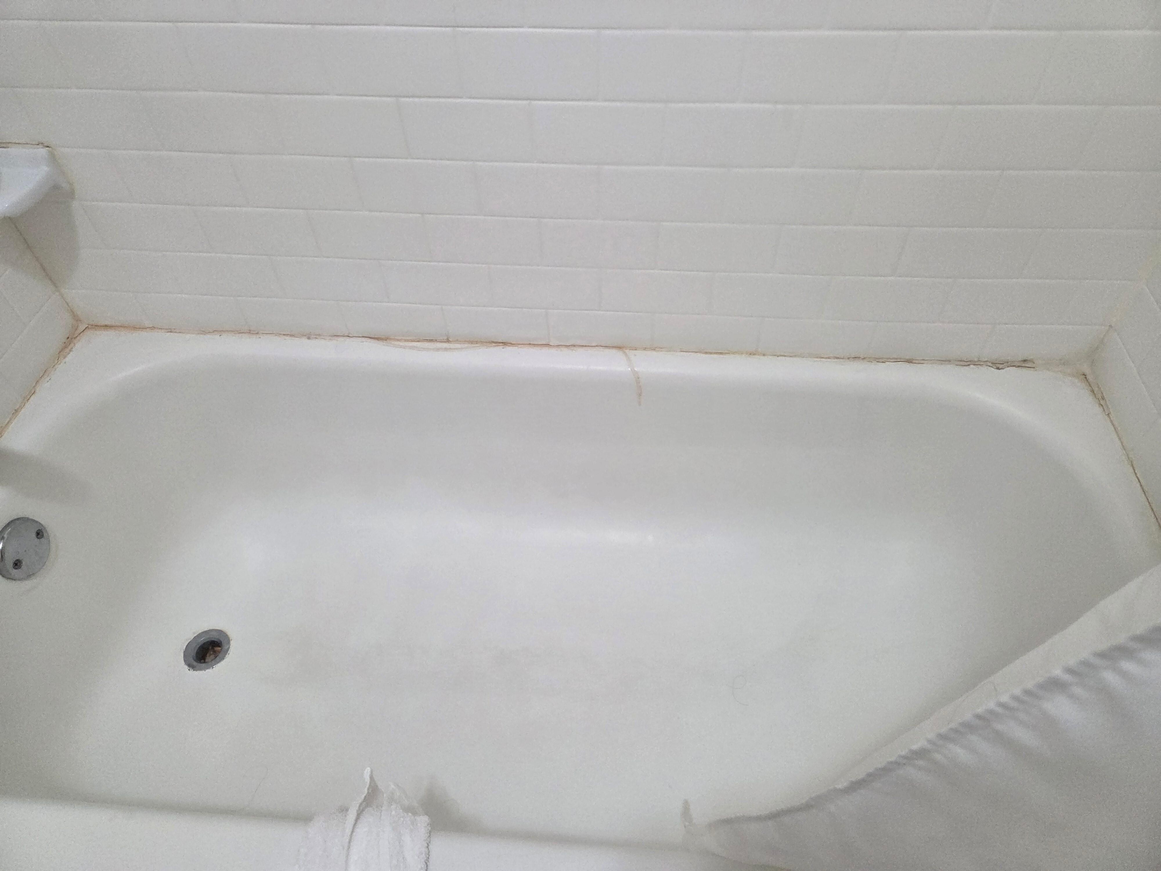 Old caulking peeling off bathtub 