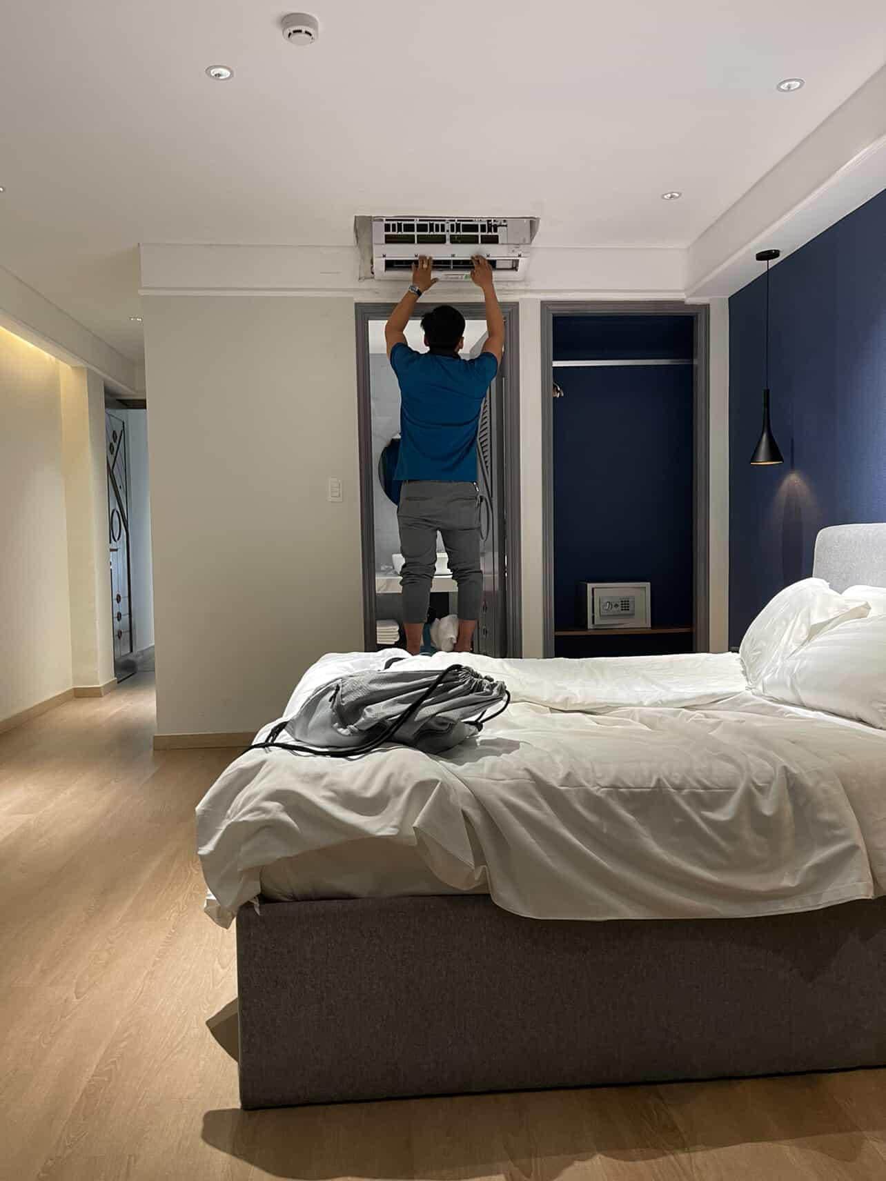 Photo shows repairman on my nightstand with no shoes standing barefoot trying to fix the AC. 