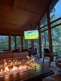 Screened in porch with gas fire pit and large TV.