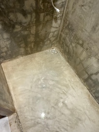 Banheiro com o ralo do banheiro totalmente entupido.