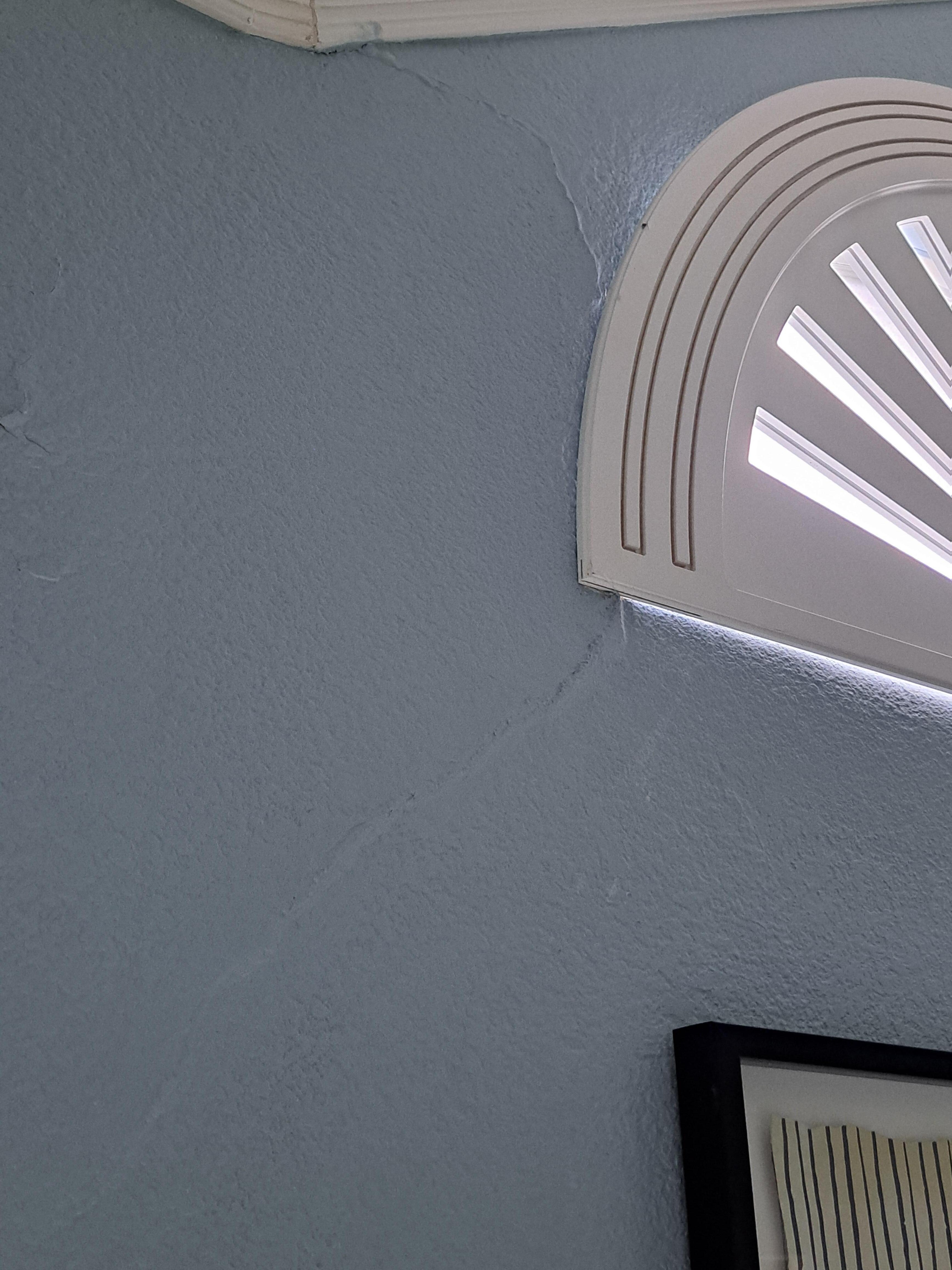 A badly repaired cracked in the wall in the primary bedroom. There's cracking in most of the rooms' ceilings.