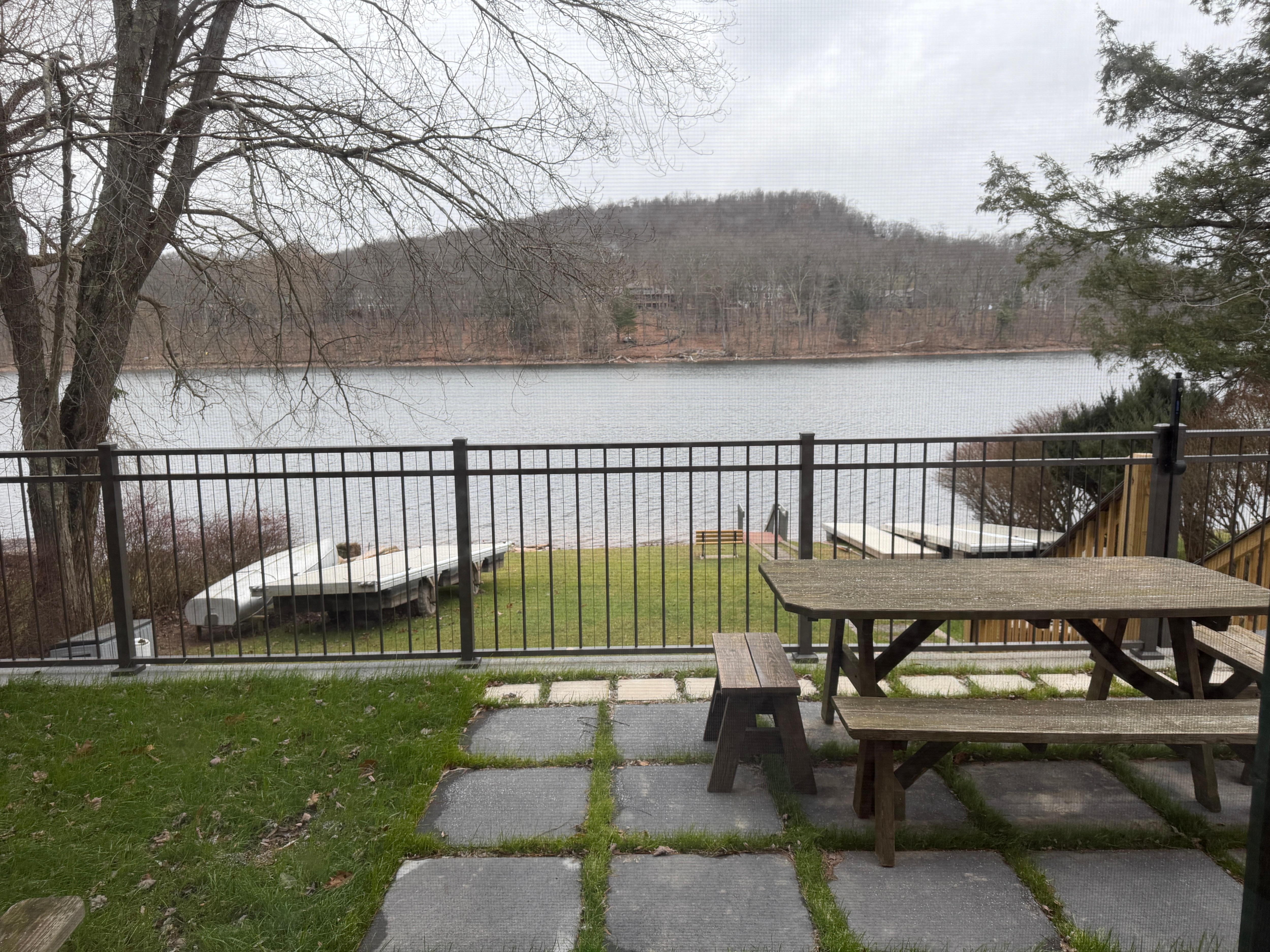View of lake from fenced yard with picnic table hot tub and dog area 