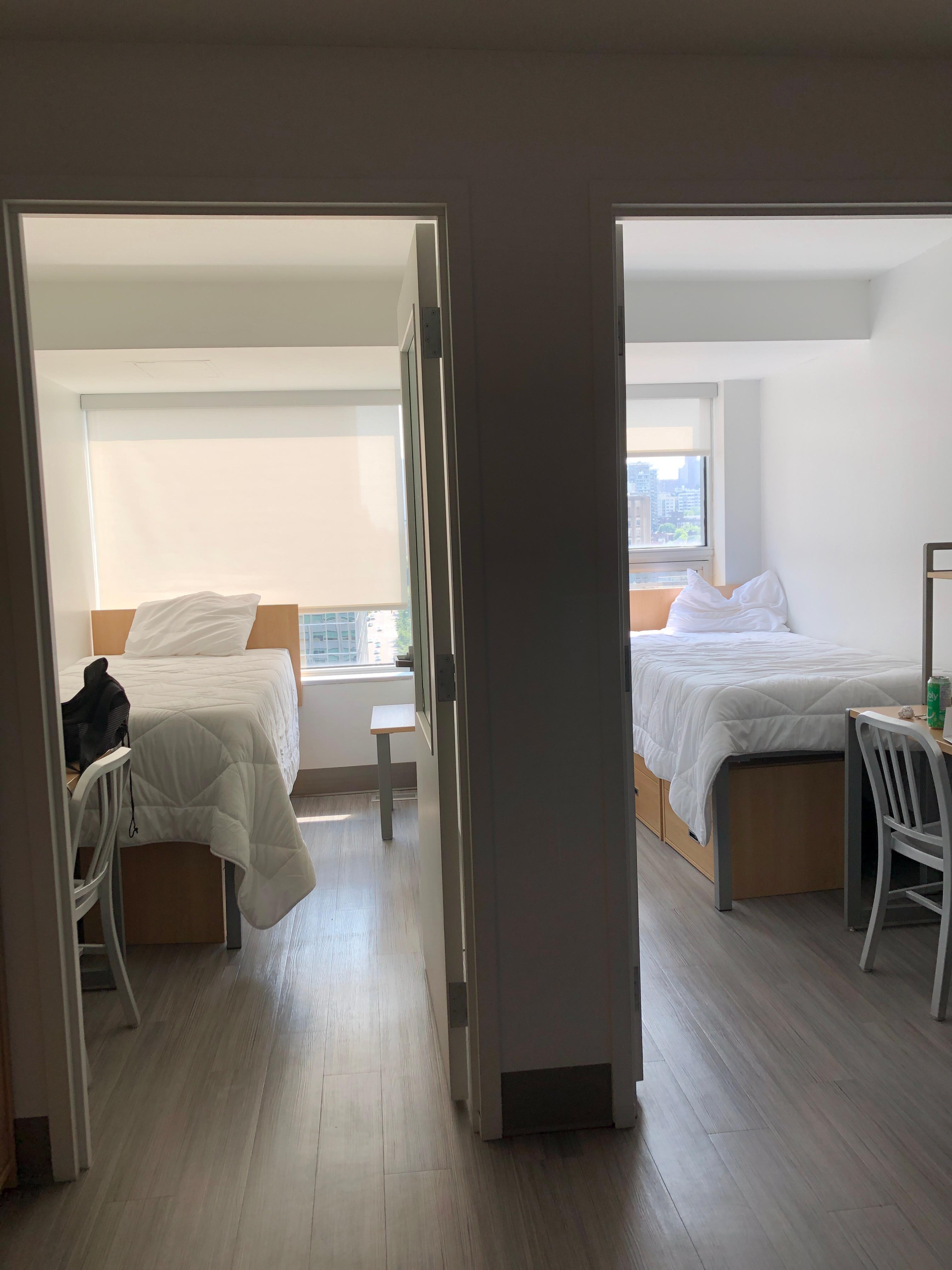 Two separate rooms with a twin bed and a desk in each.