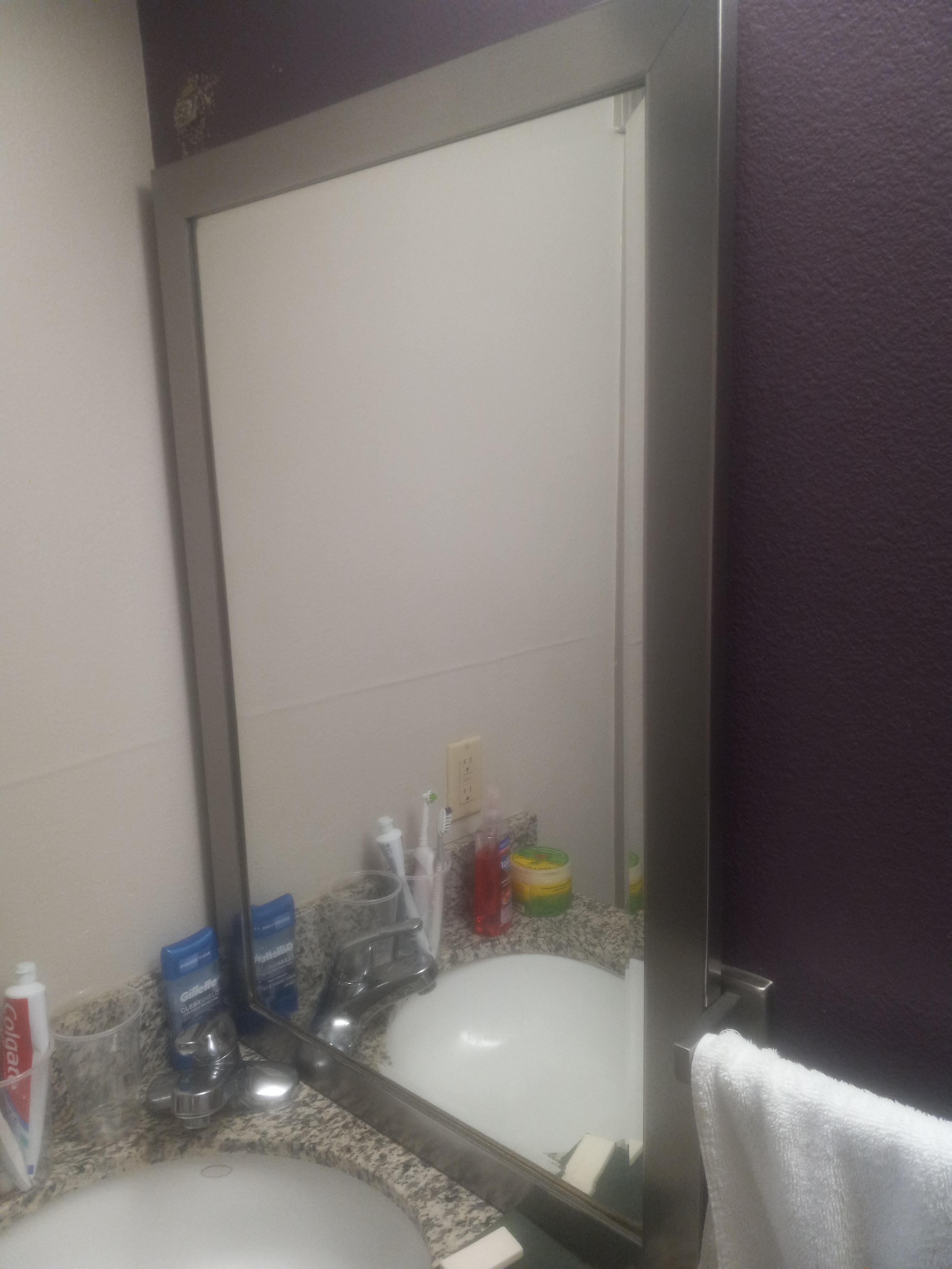 Broken mirror off hindges sitting on counter.