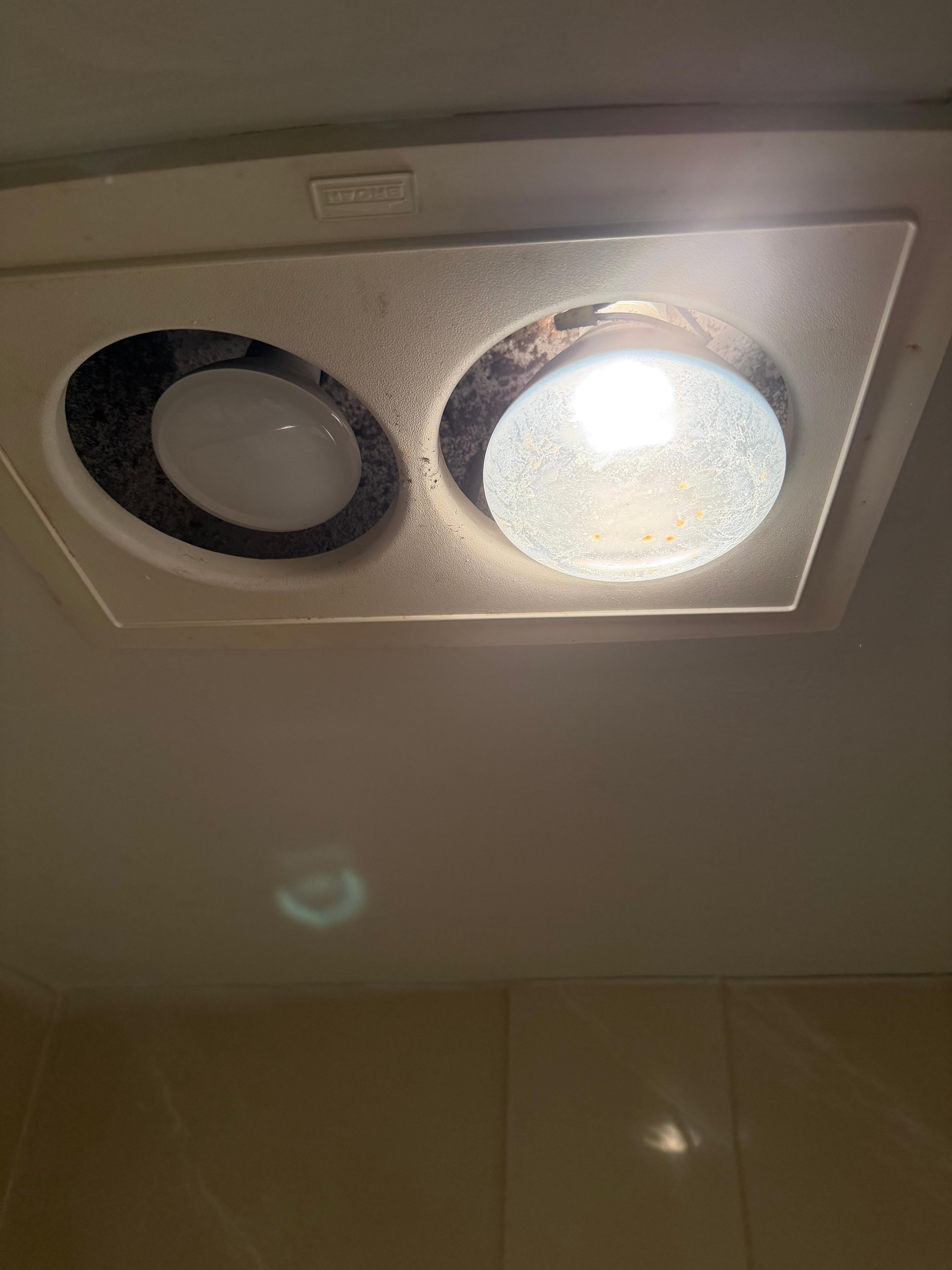Huge heat lamp and smaller dim light in bathroom with a huge gap 