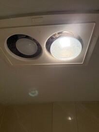 Huge heat lamp and smaller dim light in bathroom with a huge gap