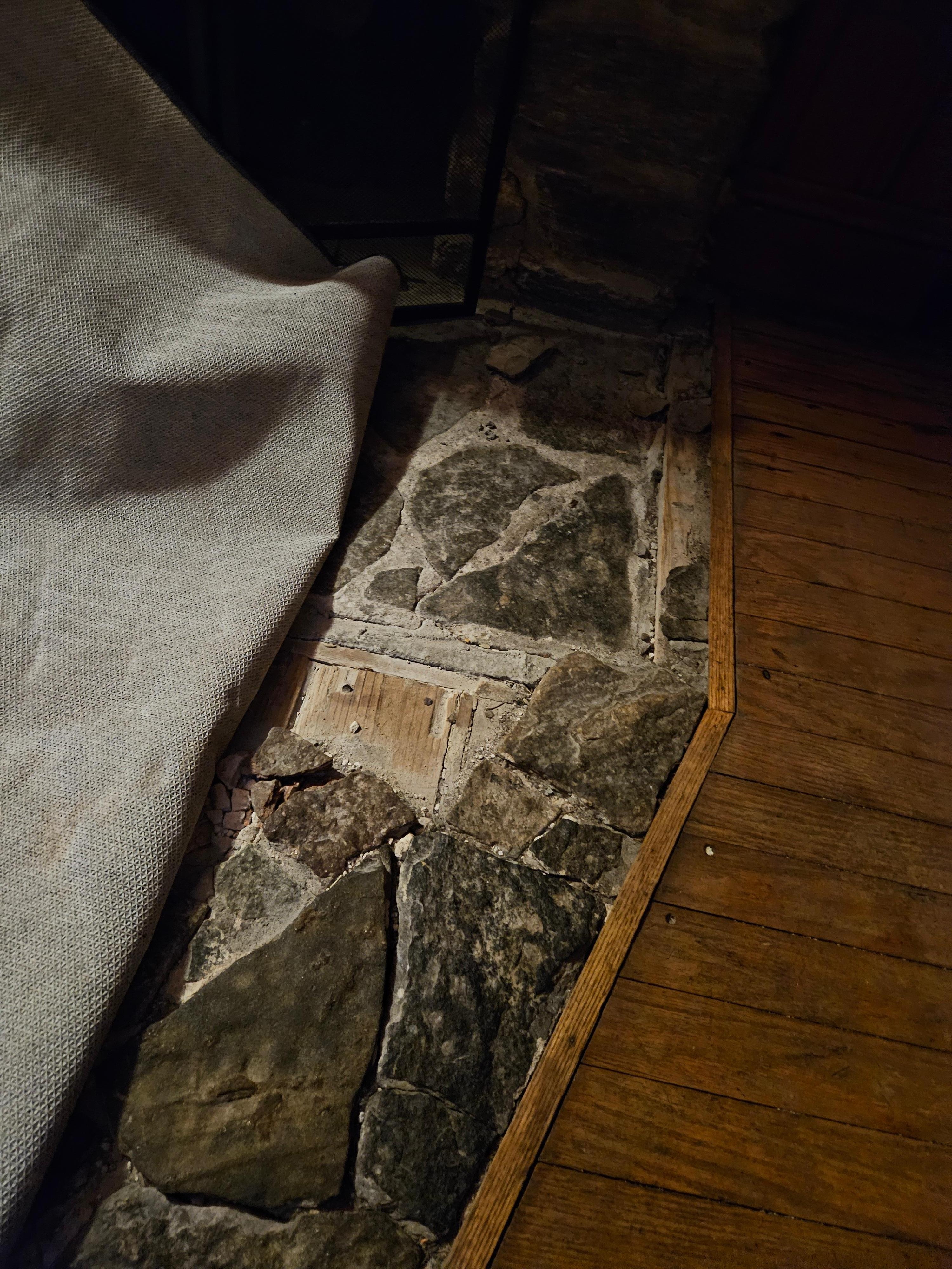 Broken flooring in front of fireplace that cause a  fall due to it being hidden by a throw rug