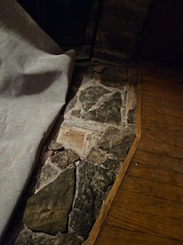 Broken flooring in front of fireplace that cause a  fall due to it being hidden by a throw rug