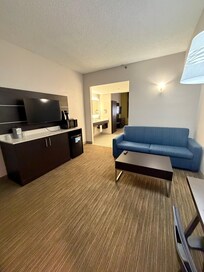 Living area with TV, sofa, fridge, microwave, coffee maker and desk