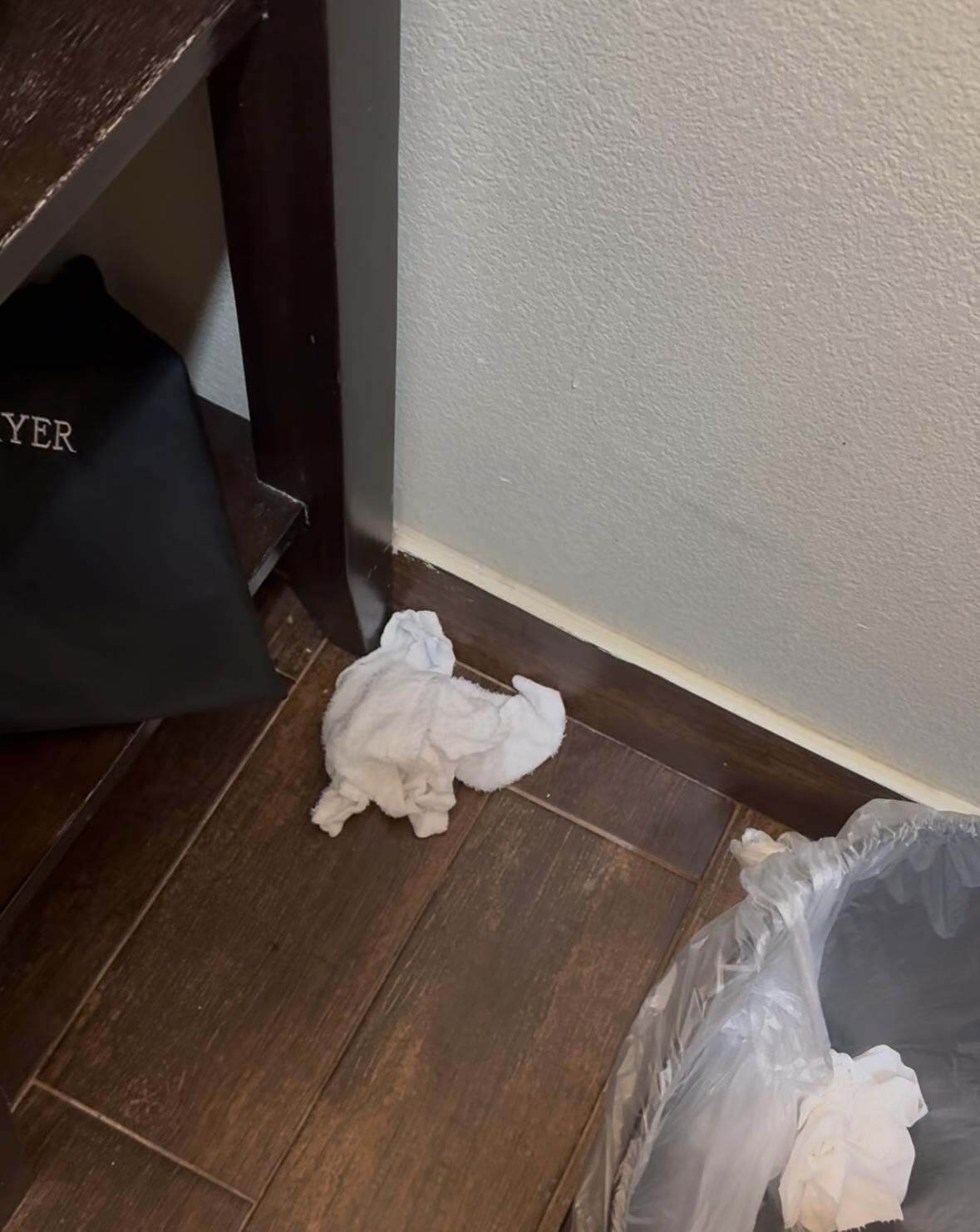 Dirty rag left on floor in corner in bathroom 