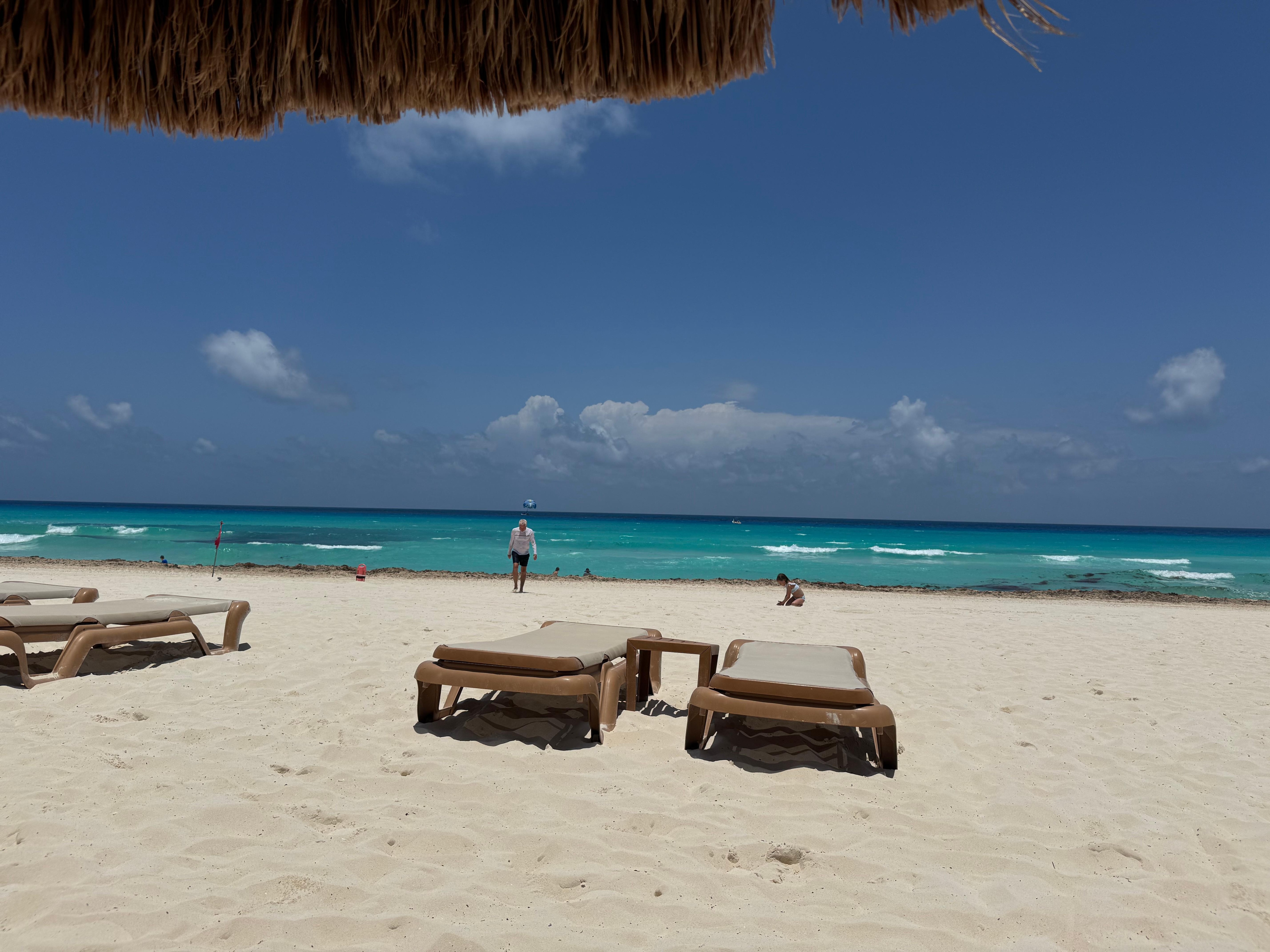 Tiki umbrellas on beach with loungers and service