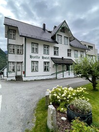 Her er et bilde av Hjelle Hotel, som viser det sjarmerende sveitserstil-hovedbygget fra 1896 og den pittoreske beliggenheten ved Oppstrynsvatnet.