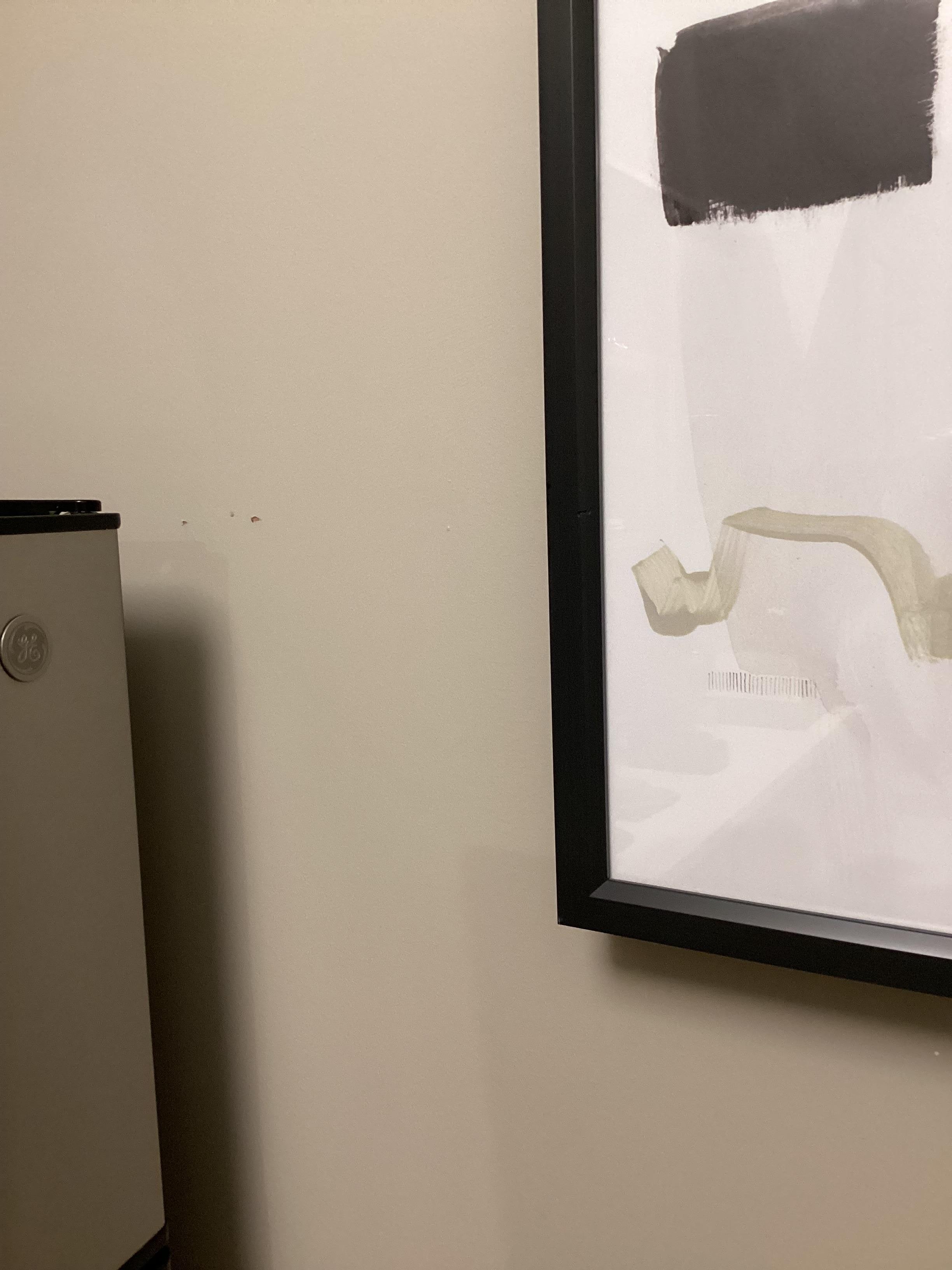2 small holes in the wall between the picture and the fridge