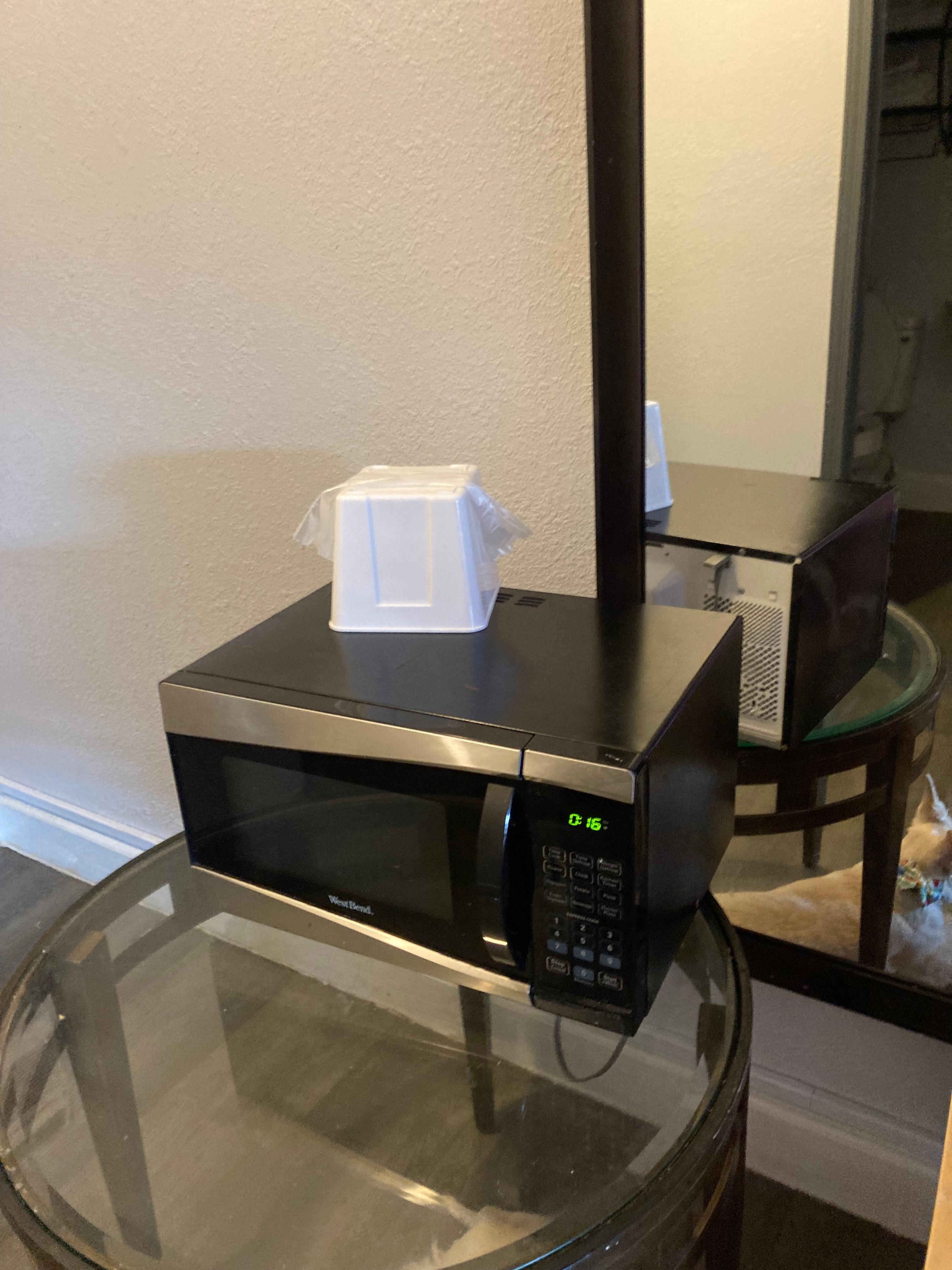 Microwave balanced on a glass table. 