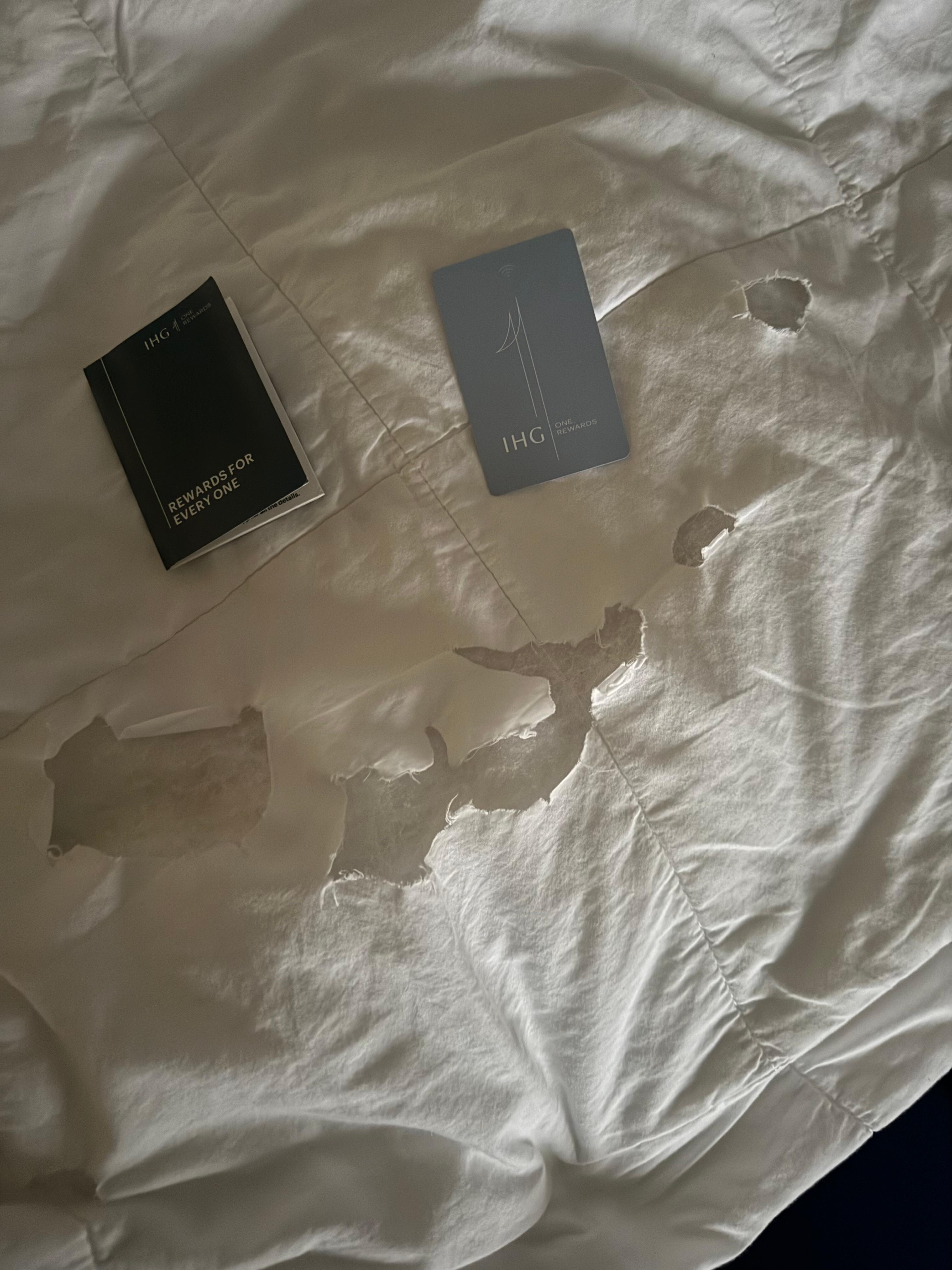 More holes in the blanket next to the hotel key card to show how big the holes are and that it is in fact the hotel blanket 