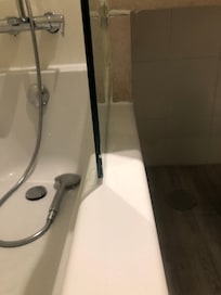 Wasser läuft von der Duschtrennwand in‘s Bad