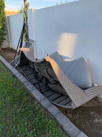 Broken patio furniture and yard game equipment leaning against the wall.