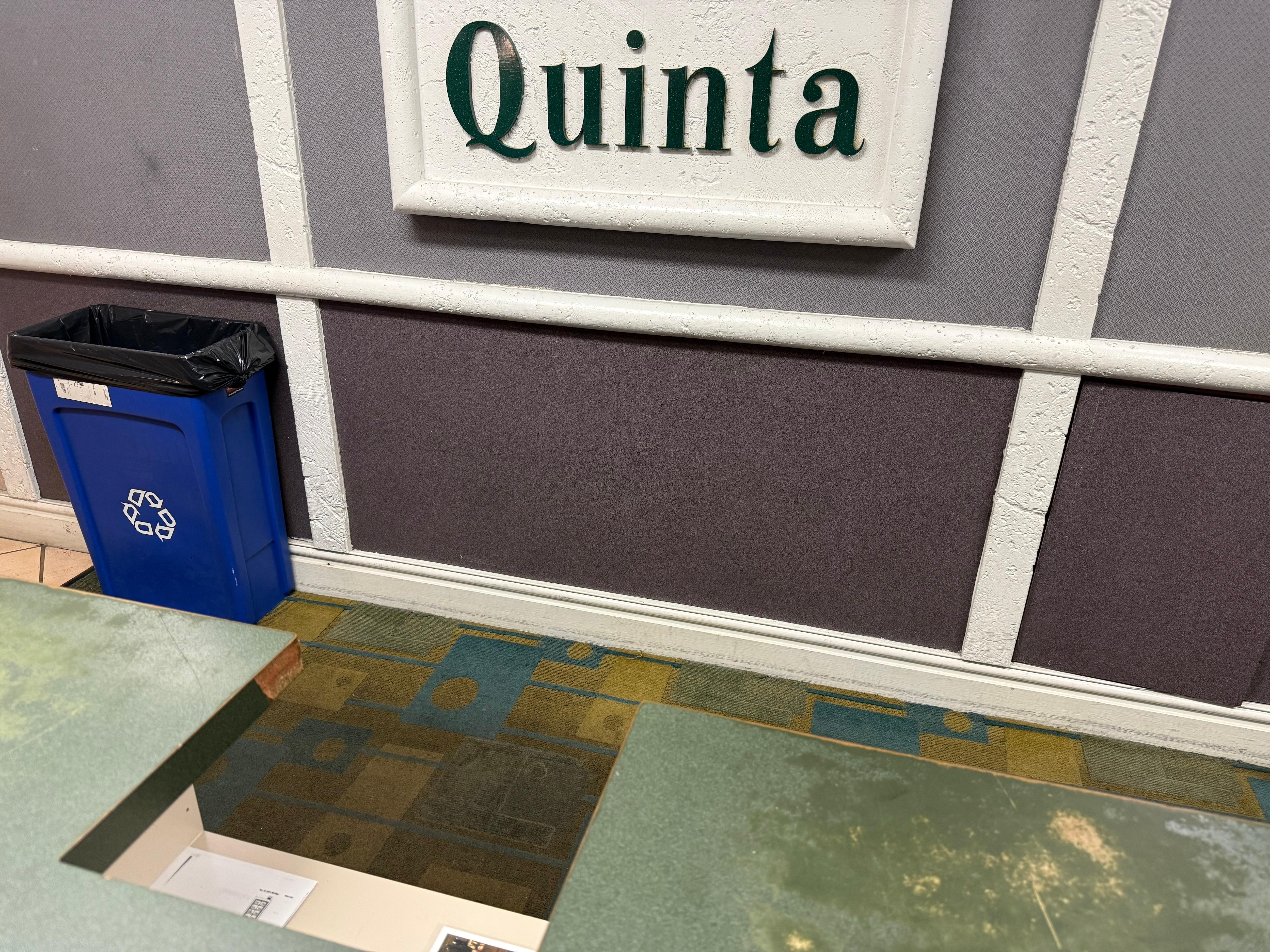 Registration desk worn down, broken edges. Wall has loose panels.