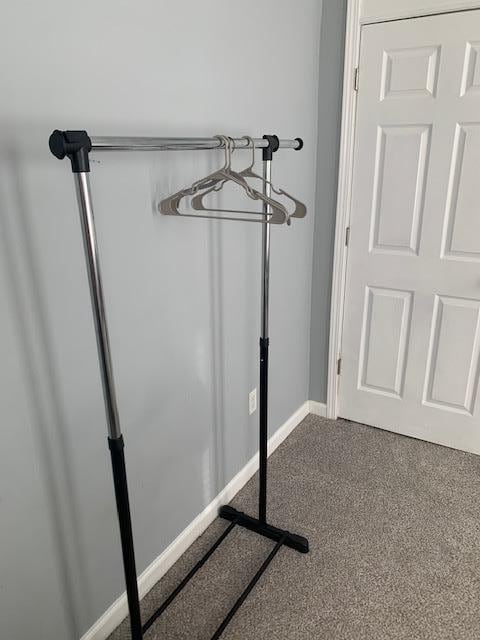 There is a clothes rack in the bedroom of the smaller bed.
