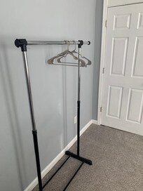 There is a clothes rack in the bedroom of the smaller bed.