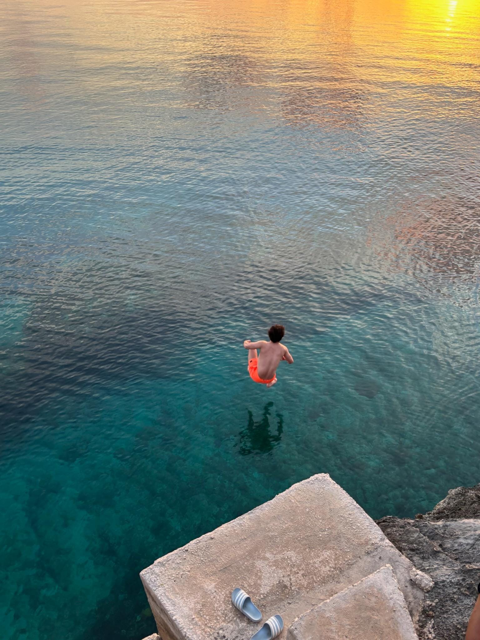 Jumping into the clear blue sea from the landing at sunset, just steps away from the house
