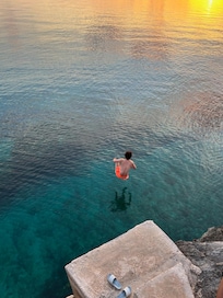 Jumping into the clear blue sea from the landing at sunset, just steps away from the house
