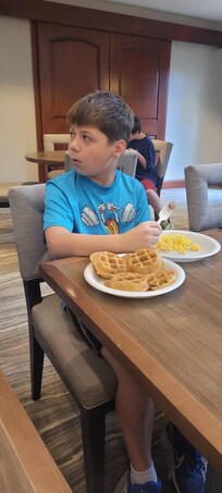 Good morning breakfast with sausage, eggs, bread, yogurt, waffles, beverages, cereals